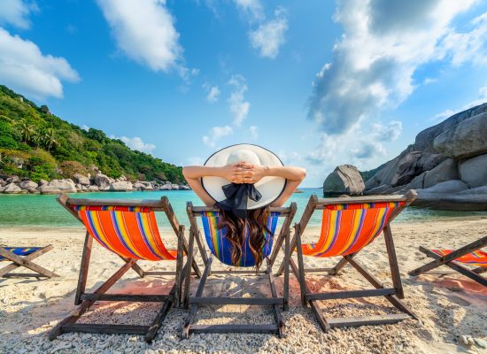 Woman with hat sitting on chairs beach in beautiful tropical beach. Woman relaxing on a tropical beach at Koh Nangyuan island.